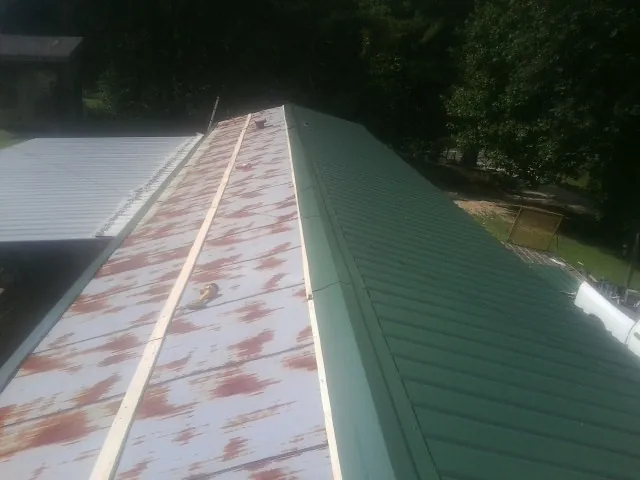 Old rusted panels beside newly installed green metal roofing — Wind Damage Roof Repair by Roofing Brothers in Oceanport