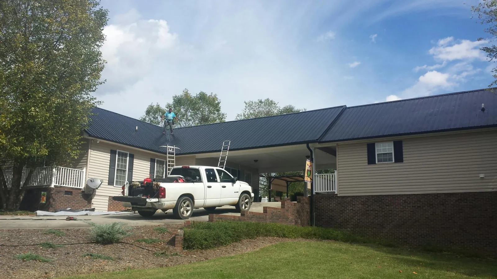 Black metal roof over a home and attached breezeway with ladders set in Oceanport