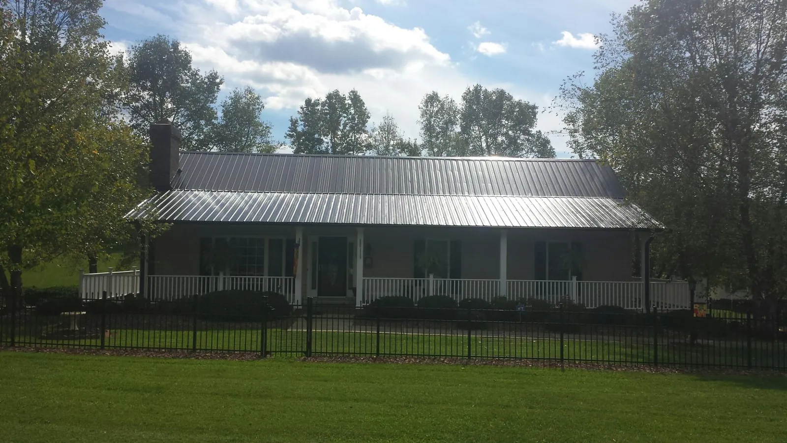 Gray metal roof on a brick ranch with a full width front porch — Gutter Guard Installation work by our crew in Oceanport