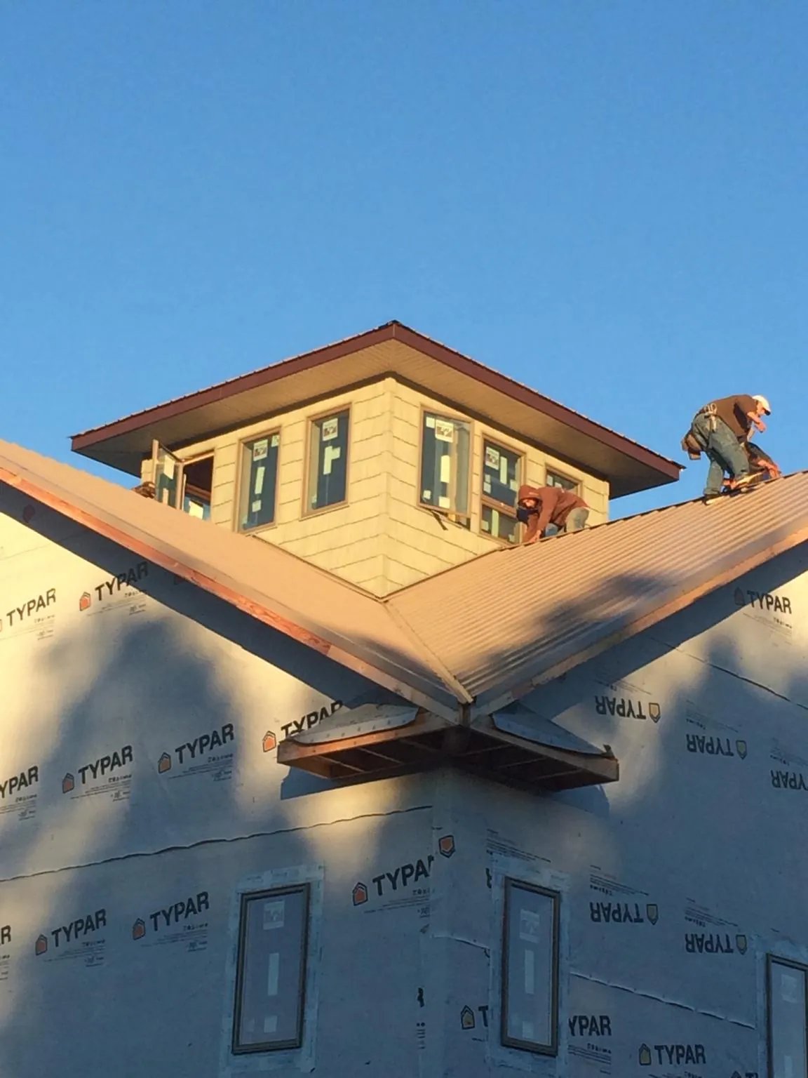 Roofers working around a rooftop cupola on a new metal roof at sunset — Roof Waterproofing in Oceanport by Roofing Brothers